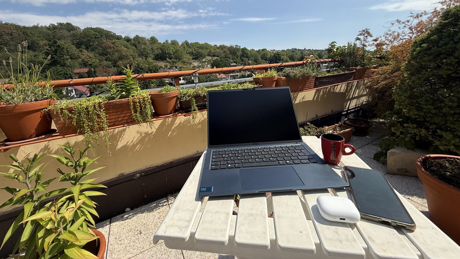 Laptop, phone, AirPods and espresso on an outdoor terrace