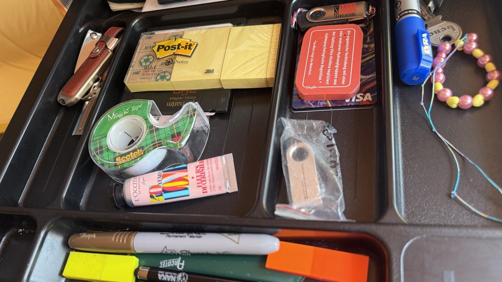 Everyday supply drawer with Post-it notes, pens, tape and other stationery.